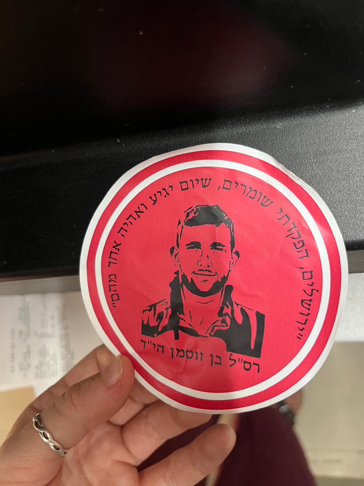 A red sticker shows the face of an Israeli soldier, alongside Hebrew text.
